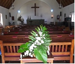 Inside the chapel: wooden pews and white flowers beneath a cross